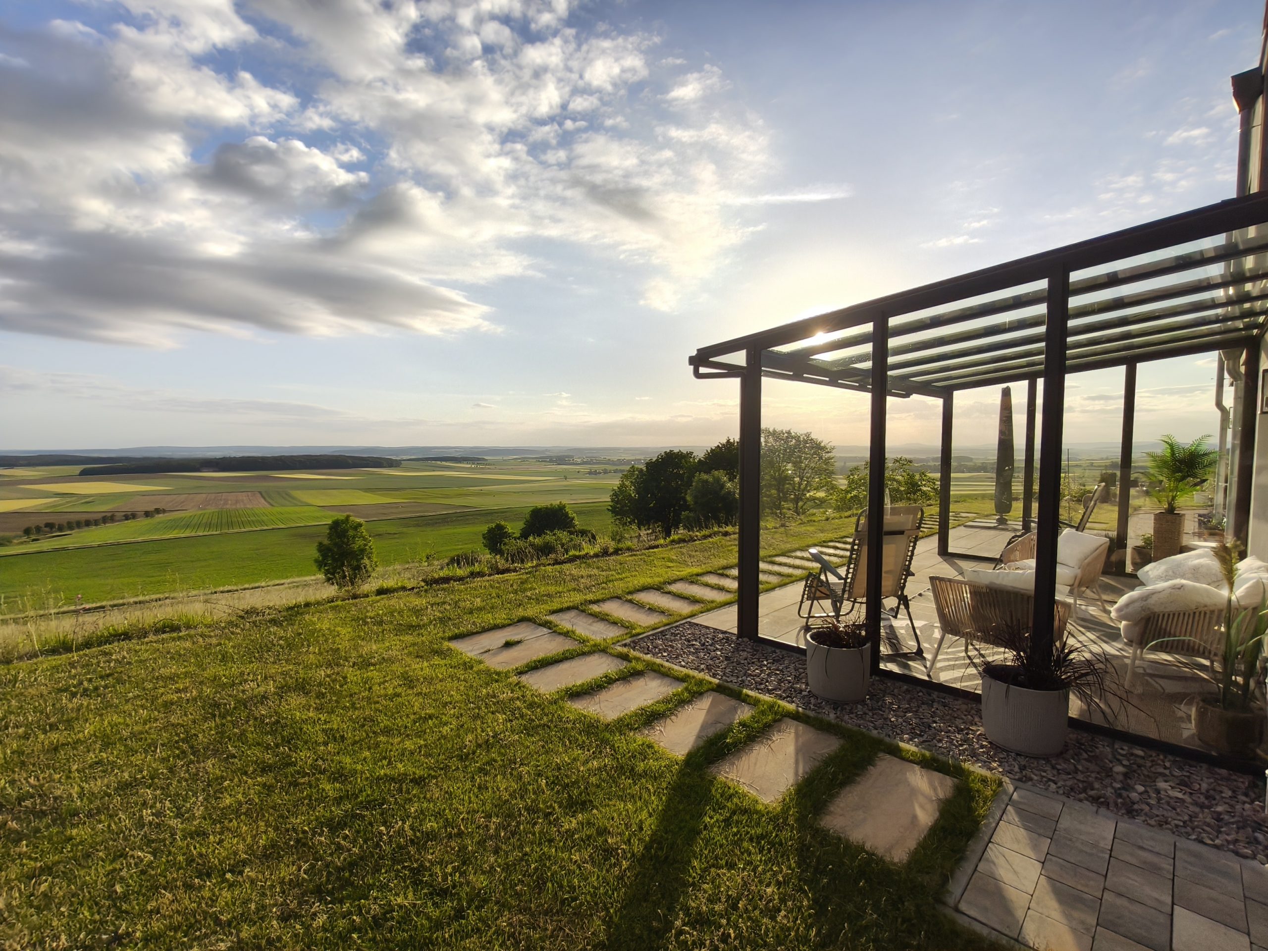 Große Terrasse mit Überdachung und Panoramablick über Felder im Morgenlicht