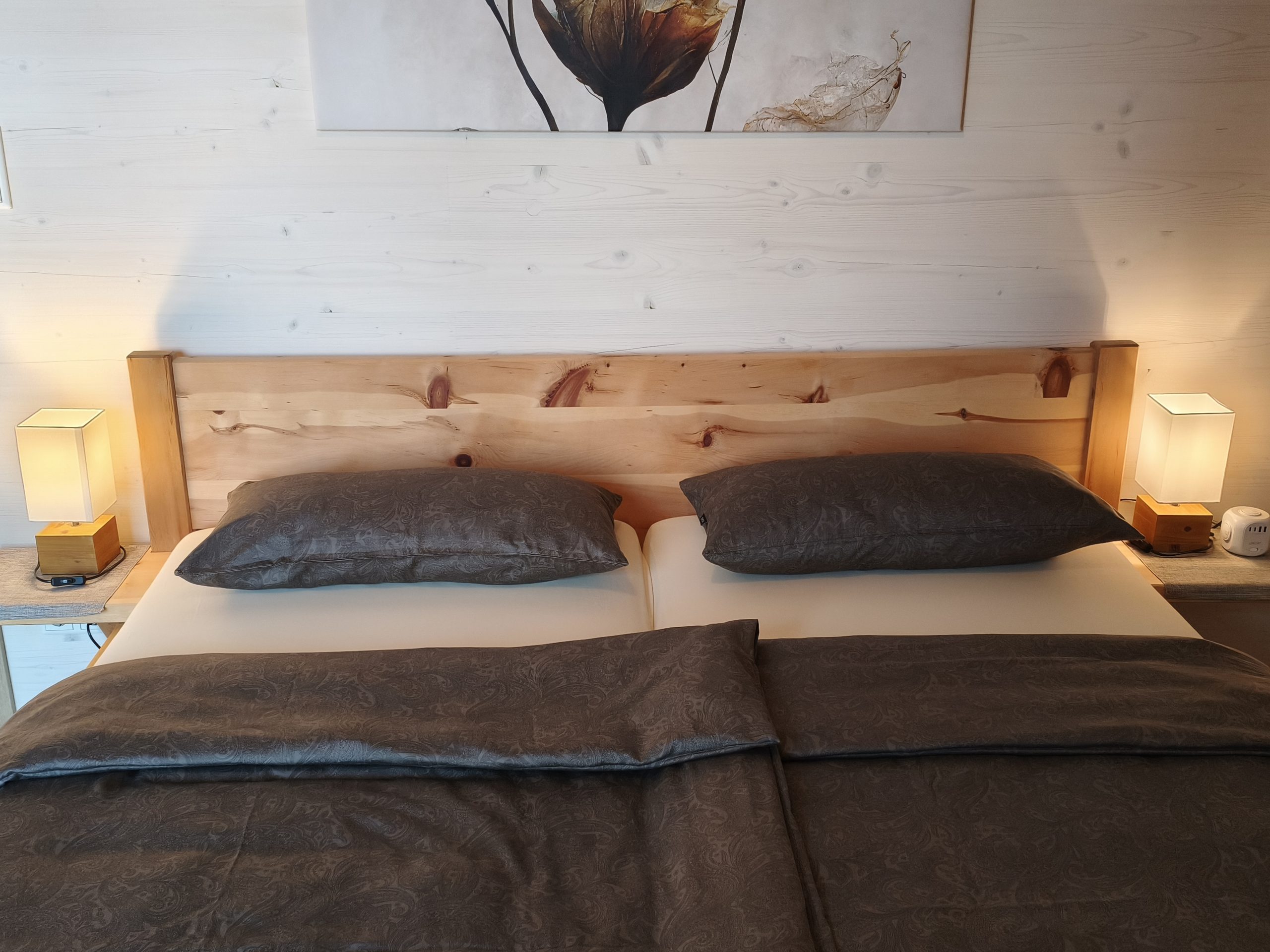 Hauptschlafzimmer mit Zirbenbett Großes Zirbenbett im Hauptschlafzimmer von Apartment 2 mit warm beleuchteten Nachttischlampen